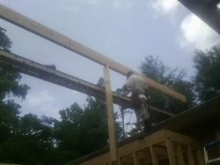 Carpenter setting a ridge beam over a new addition frame — Ice Dam Removal by Roofing Brothers in Wichita