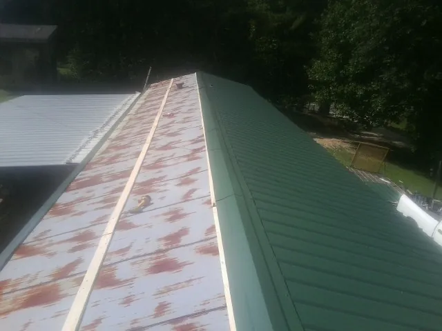 Old rusted panels beside newly installed green metal roofing — Wind Damage Roof Repair by Roofing Brothers in Wichita