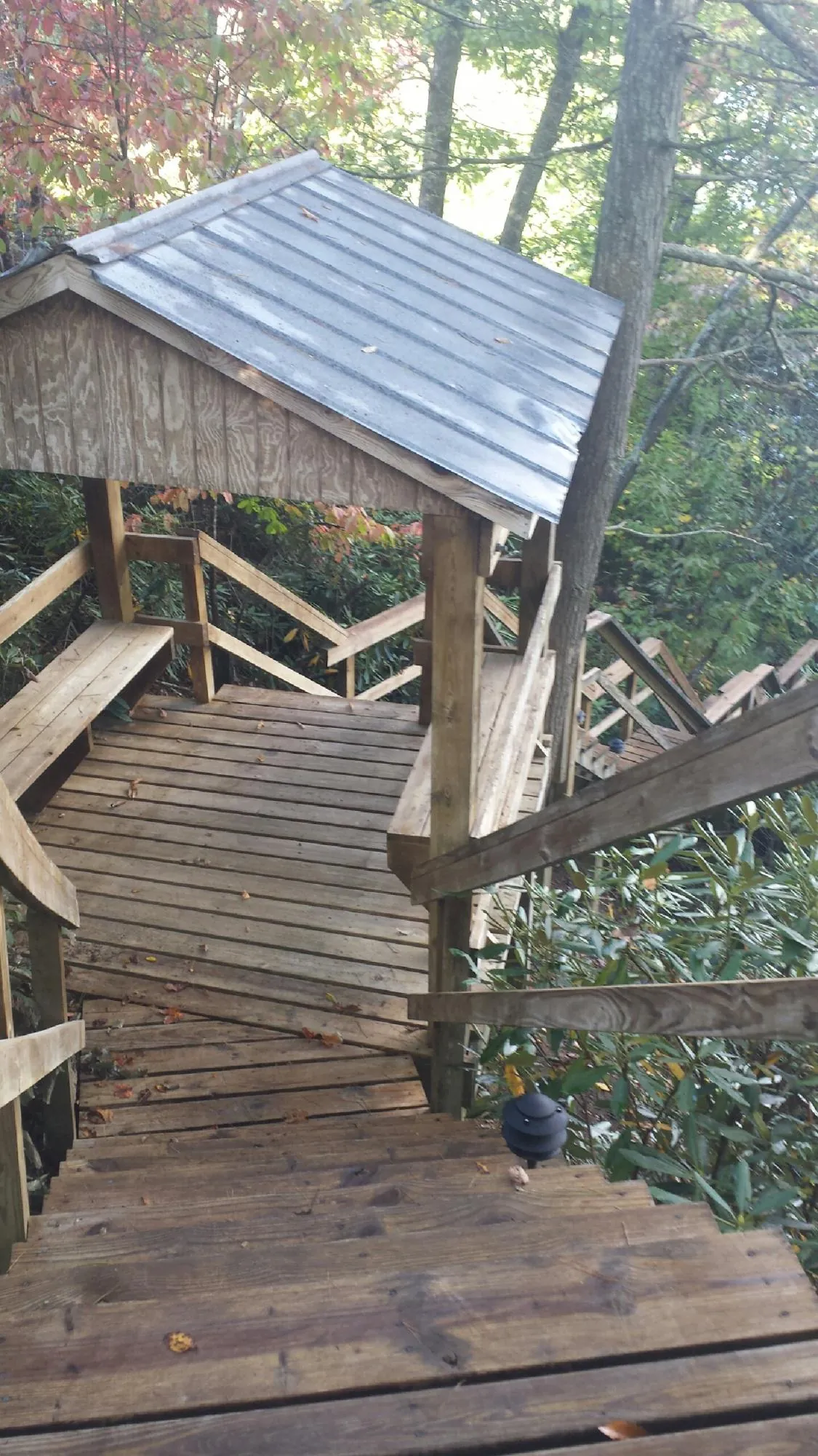 Metal roofed shelter over wooden steps on a wooded walkway — Skylight Repair & Installation work by our crew in Wichita
