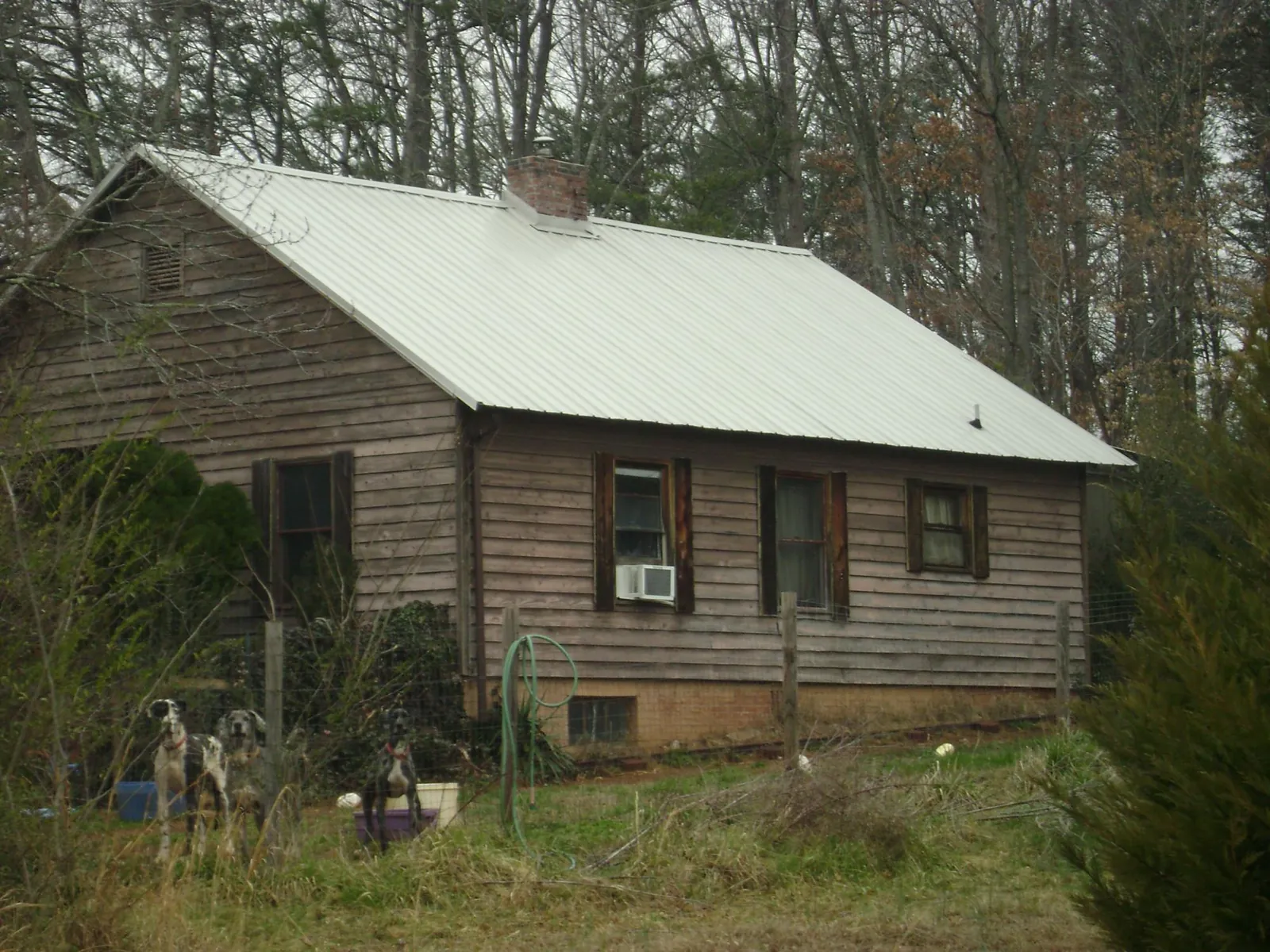 White metal roof on an old wood sided farmhouse, from a Metal Roof Installation job in Wichita