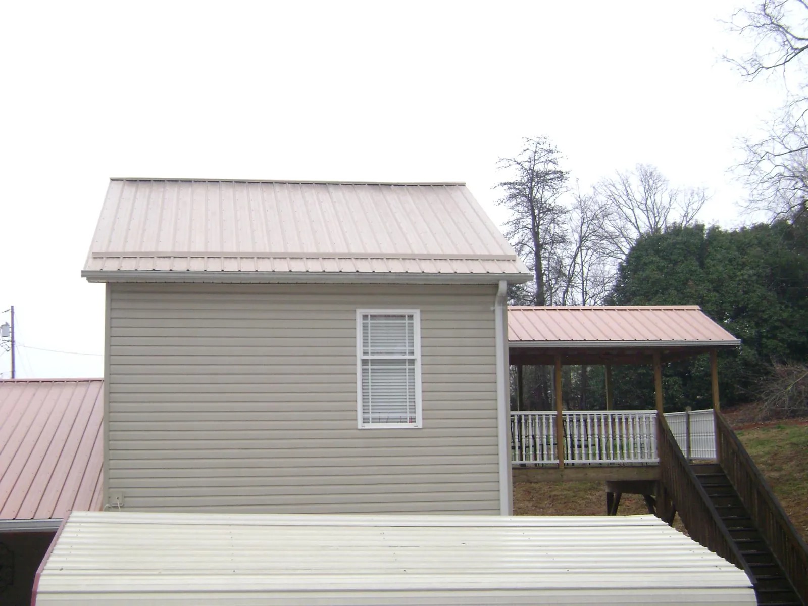 Tan metal roofs on a two story addition and attached porch, from a Roof Replacement job in Wichita