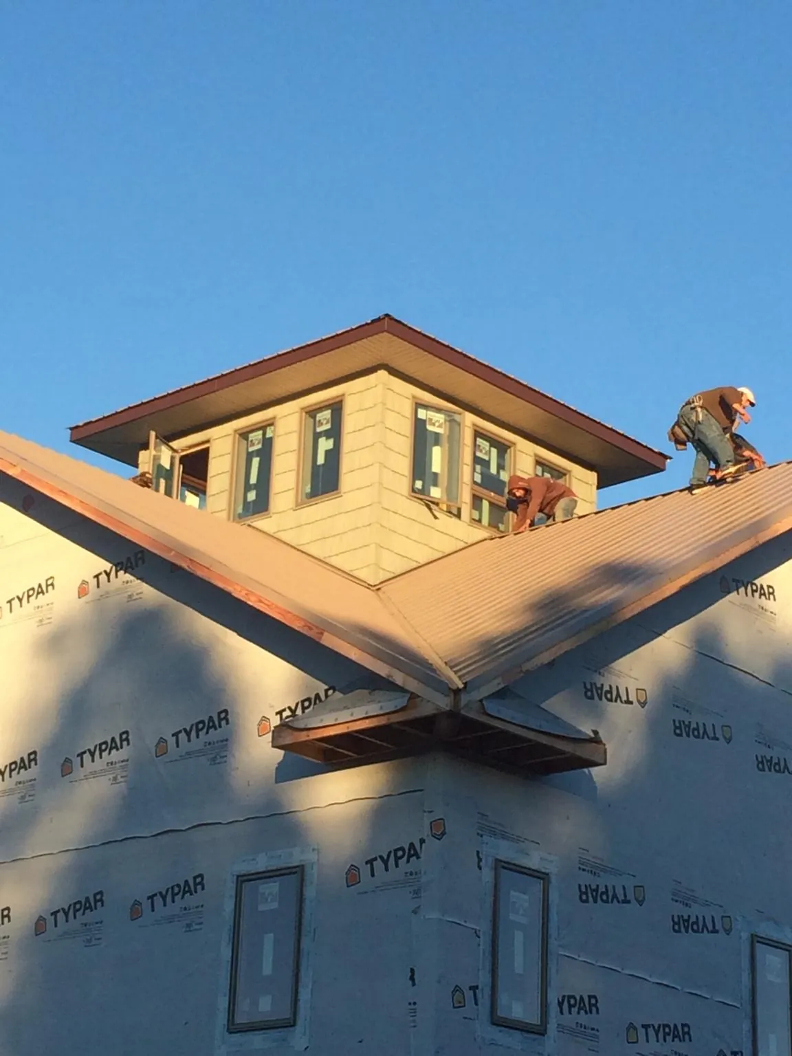 Roofers working around a rooftop cupola on a new metal roof at sunset — Roof Waterproofing in Wichita by Roofing Brothers